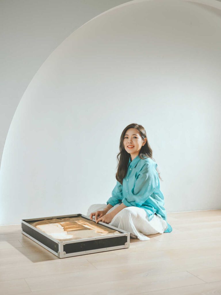 在香港的藝術界,鍾雪是一位別具一格的創作者。她不是用畫筆,而是用沙子,把一個又一個動人的故事呈現在觀眾眼前。從2015年開始,她不只是一位沙畫藝術家,更是一位推動者,她成立了香港沙畫協會、創辦全球首個沙畫體驗館,並領導全港第一個分級考核沙畫證書學院。這一切的起點,源於她對故事的熱愛和對沙畫無限可能的堅信。