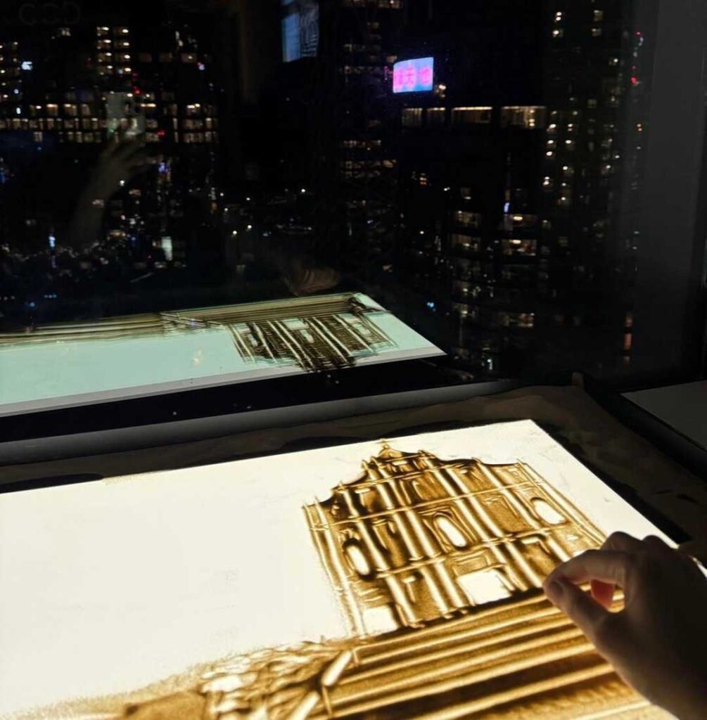 在香港的藝術界,鍾雪是一位別具一格的創作者。她不是用畫筆,而是用沙子,把一個又一個動人的故事呈現在觀眾眼前。從2015年開始,她不只是一位沙畫藝術家,更是一位推動者,她成立了香港沙畫協會、創辦全球首個沙畫體驗館,並領導全港第一個分級考核沙畫證書學院。這一切的起點,源於她對故事的熱愛和對沙畫無限可能的堅信。