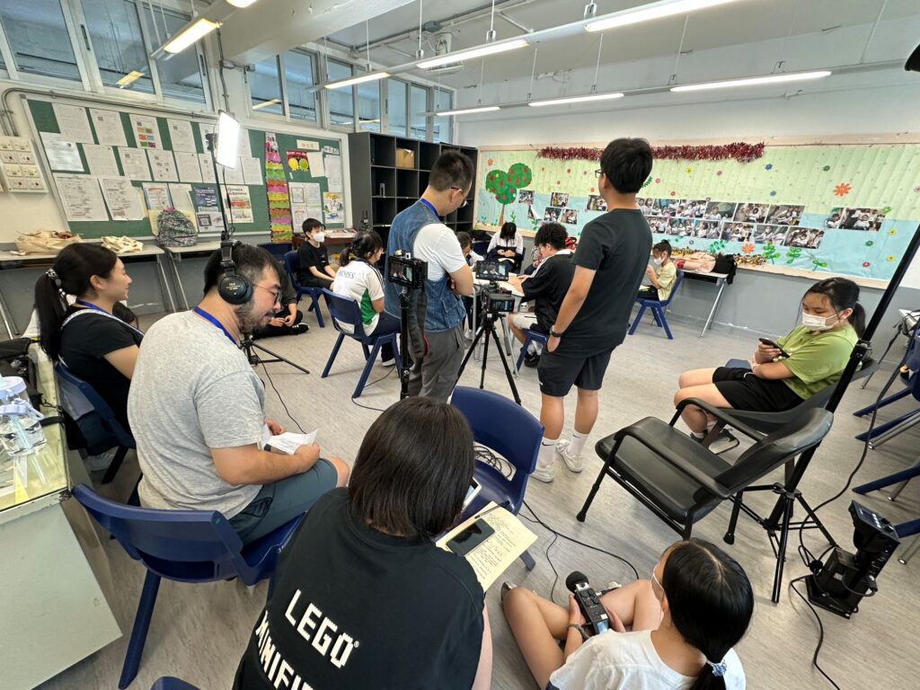 在炮台山循道衛理中學,有一位老師選擇以影像喚起社會對青少年的理解與關注。她就是李天慧老師,學生們親切地稱她為 「Miss Vicky」 或「小V老師」。在教學崗位之外,Vicky默默推動一項深具意義的創作計劃——她以學生的生命故事為藍本,製作了一系列微電影。透過這些影像作品,一群常被忽略的特殊教育需要(SEN)學生,得以表達自己,讓公眾重新認識他們的堅持與潛能。這不僅是一位老師的努力,更是一份對生命的理解與尊重。