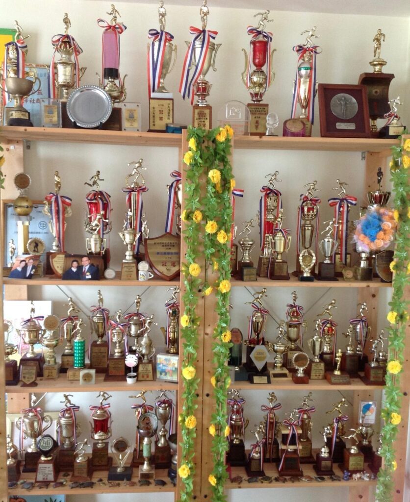 有些人談運動，談的是身形；繆彩蘭談運動，談的卻是人生。她十歲開始跑步，十八歲踏上講台，四十多年來把課堂搬進社區、把節奏帶進日常，也把「堅持」這兩個字，教到一代又一代人心裡。命運曾在她最熟悉的跑道上突然按下急停——一場主動脈瘤手術，讓她不得不重新認識身體、重新安排生活；但她沒有退場，反而更篤定地走回人群之中：陪長者鍛鍊、到學校、機構分享，甚至自掏腰包辦活動，只為讓更多人願意踏出第一步。這次專訪，我們沿著她的步伐回望：一個把運動做成信念的人，如何在起伏裡把自己站穩，也把別人扶起來。