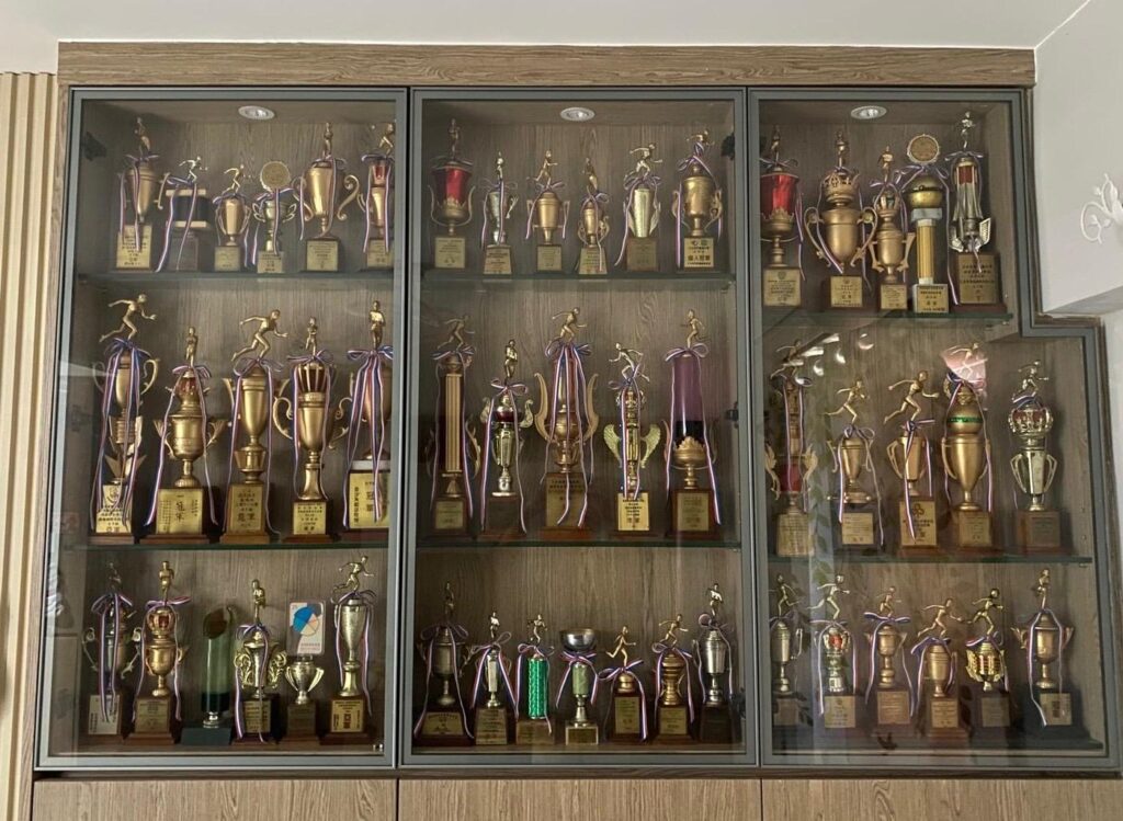 有些人談運動，談的是身形；繆彩蘭談運動，談的卻是人生。她十歲開始跑步，十八歲踏上講台，四十多年來把課堂搬進社區、把節奏帶進日常，也把「堅持」這兩個字，教到一代又一代人心裡。命運曾在她最熟悉的跑道上突然按下急停——一場主動脈瘤手術，讓她不得不重新認識身體、重新安排生活；但她沒有退場，反而更篤定地走回人群之中：陪長者鍛鍊、到學校、機構分享，甚至自掏腰包辦活動，只為讓更多人願意踏出第一步。這次專訪，我們沿著她的步伐回望：一個把運動做成信念的人，如何在起伏裡把自己站穩，也把別人扶起來。