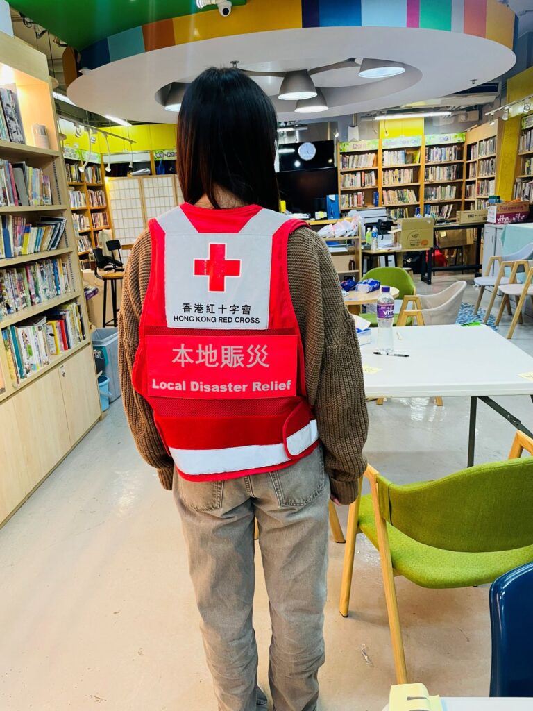 宏福苑火災後,避難中心裡的人需要的往往不是更多指令,而是一個能讓情緒慢慢落地的陪伴。關靜文Queenie從下午四點守到翌日清晨六點,十多個小時不斷巡視災民:有人因燈光難以入睡,她用兩塊布和夾子替他遮出一個能安心休息的角落;一個一年級男孩走來請她出幾道數學題,竟成了孩子在驚嚇後第一次重新開口;而在更沉重的時刻,她也陪家屬走過認領遺體的路。這篇文章想寫的不是英雄傳,而是那些看似微小、卻能在混亂裡撫慰人心的行動。