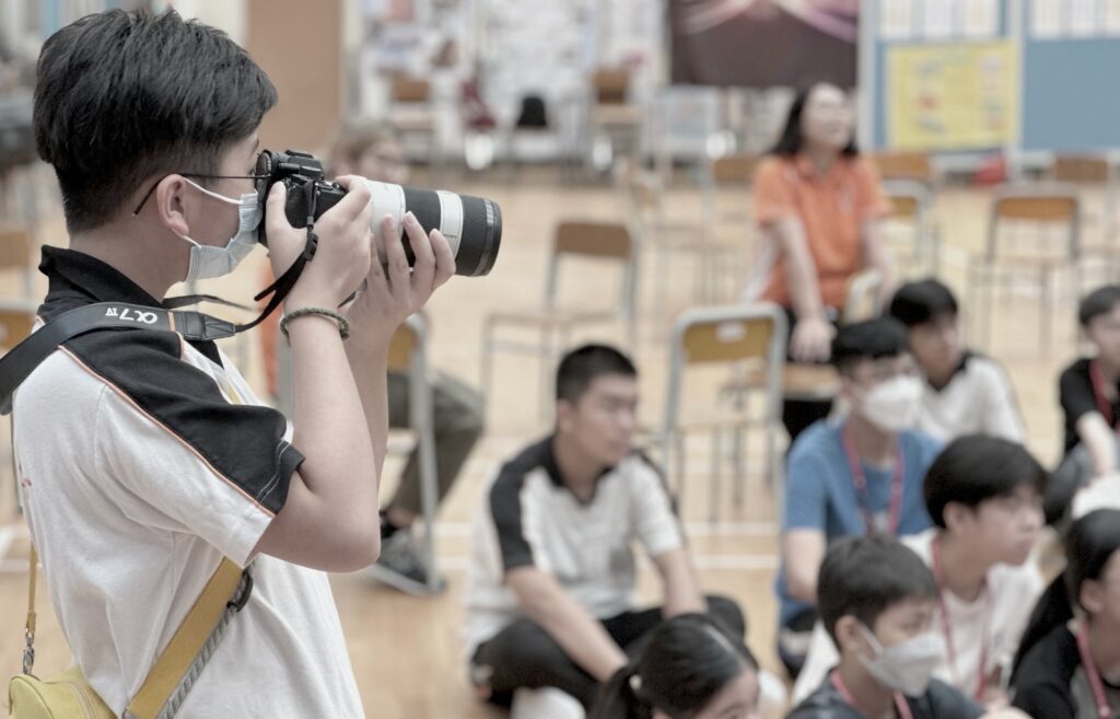 姜少聰 Samuel 原本是一位設計師,從事印刷、廣告到室內設計,事業發展穩定,卻在一次突如其來的身體警號下重新思考人生方向。他沒有選擇繼續向上爬,而是走進社會的邊緣,在非牟利機構 兒童樂園基金會 創立了Project C&C,專門為SEN(特殊教育需要)學生提供攝影、拍片和媒體創作課程。十年來,他一直營運整個項目,走入學校、院舍和社區,透過創意教育陪伴一群被忽略的年輕人重新建立自信與目標。他相信,教育不只是教知識,更是在他們灰暗人生中點起一點光。這篇文章將帶你認識他的轉變、信仰如何引導他前行,以及這段堅持背後的故事與意義。