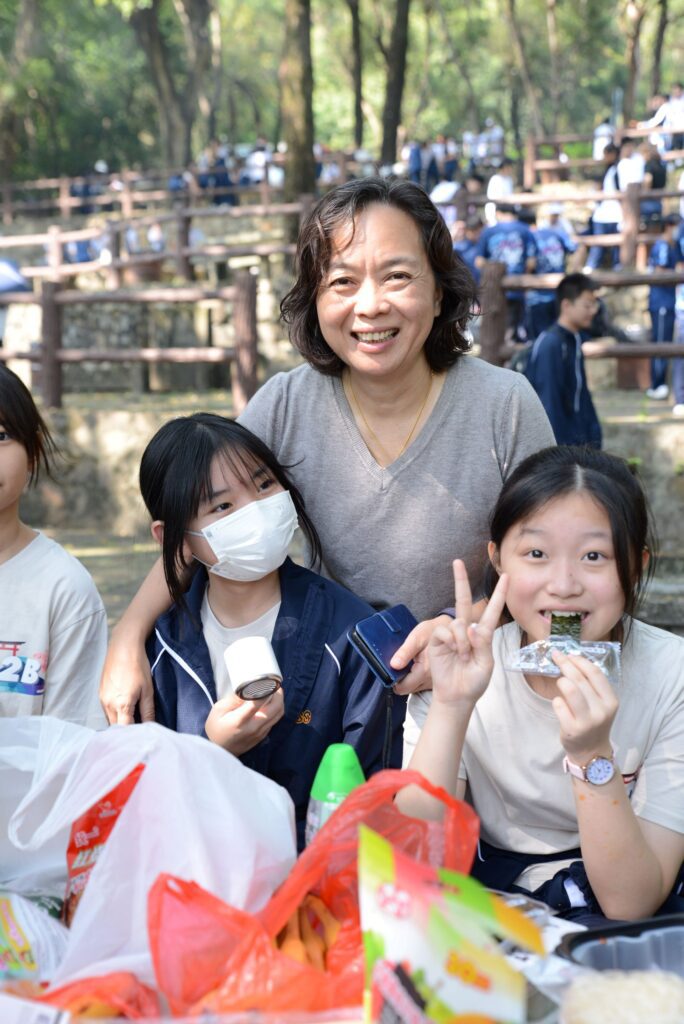 在很多人想像中,校長的日常總離不開開會、批閱文件、處理校務等;但在裘錦秋中學(屯門),陳月平校長讓人最先記住的,反而是一個很生活的畫面:午飯時間,她打開和學生一樣的飯盒,坐到他們身邊一起吃,邊吃邊聽他們聊課堂、聊朋友、聊那些一時半刻說不清的心事。她說自己也要吃學校的飯盒,因為這是責任的一部分。飯盒是否妥當、衛生是否到位、孩子吃得是否安心——這些看似細碎的事,在她眼中都不是小事。她相信教育要「落到地」,不是靠口號堆砌,而是靠每天都做得到的細節,把一間學校的溫度慢慢養出來。