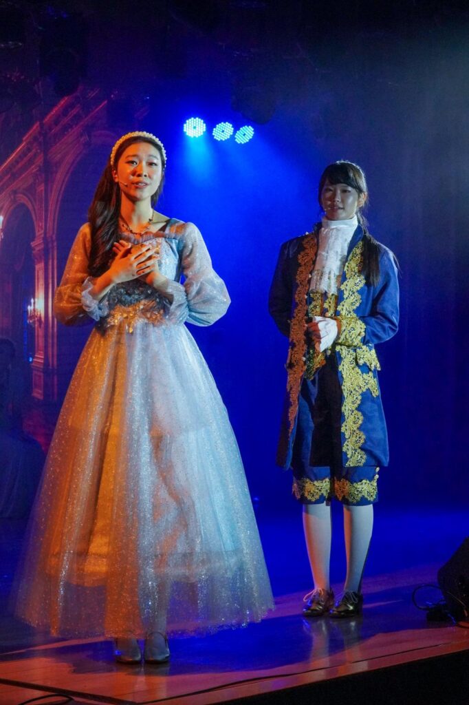 不是每一種學習都能在課室裡完成。有些能力，包括：自信、合作、承擔、面對壓力時的穩定，都需要一個更真實的場景，一群人為同一件事努力，彼此補位，然後在燈光亮起的一刻，把成果交給觀眾。鐘聲慈善社胡陳金枝中學多年來把音樂劇當作校園文化的一部分，並非為了「做一場表演」，而是刻意為學生創造一種獨特的成功感：讓他們在台前台後都能找到位置，感受到自己被需要、能做到、做得到。音樂劇也因此成為一種活動式學習——把語言、情感、價值觀與團隊精神，放進同一個具體而熱烈的練習場。