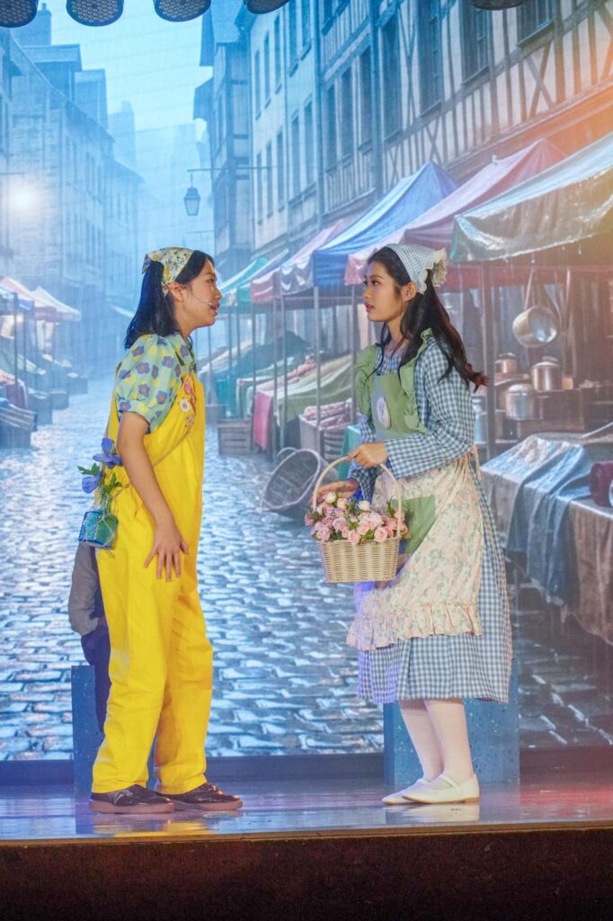 不是每一種學習都能在課室裡完成。有些能力，包括：自信、合作、承擔、面對壓力時的穩定，都需要一個更真實的場景，一群人為同一件事努力，彼此補位，然後在燈光亮起的一刻，把成果交給觀眾。鐘聲慈善社胡陳金枝中學多年來把音樂劇當作校園文化的一部分，並非為了「做一場表演」，而是刻意為學生創造一種獨特的成功感：讓他們在台前台後都能找到位置，感受到自己被需要、能做到、做得到。音樂劇也因此成為一種活動式學習——把語言、情感、價值觀與團隊精神，放進同一個具體而熱烈的練習場。