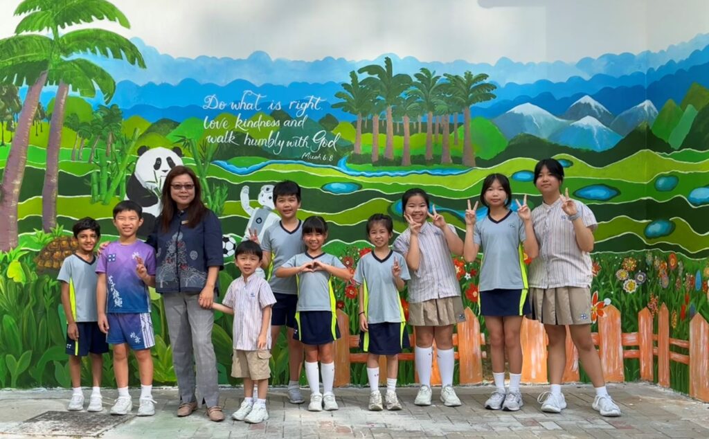 在不少家長的記憶裡,小學生活常常與成績、操練、補課和趕進度綁在一起;也有些人一直在思考:既要學得好,又要孩子身心健康,是否只能二選一?走進香港路德會增城兆霖學校,葉綠盈校長給出另一種答案,以清晰的價值為底,以課程與活動為路徑,把校園變成一個孩子願意投入、敢於嘗試、能夠成長的地方。她不把「開心」當作口號,而是把它落實到課堂設計、校本課程、交流體驗與校園空間之中,讓孩子在安全守規的環境裡玩住學、學住玩;也讓家長看見,原來一間屯門的屋邨小學,同樣可以把孩子帶向更寬廣的世界。她回想自己的教育路過去在九龍東教任教多年,來到這裡擔任校長四年,她形容自己是「好開心」的,不只是換了崗位,而是重新看見:原來上學不一定要靠催谷成績來支撐,也可以靠孩子的好奇心與投入感來推動。