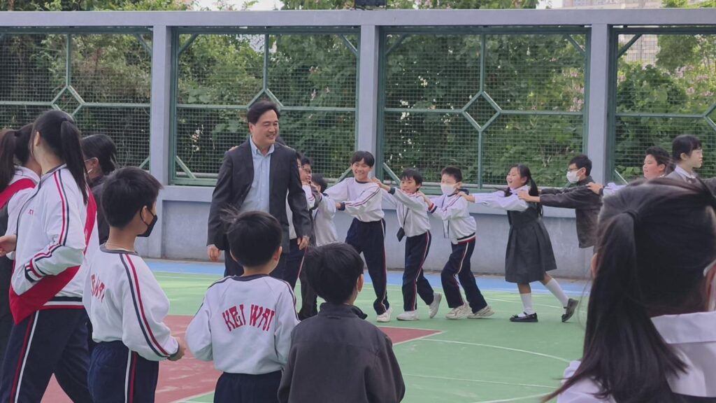 中華基督教會基慧小學 宗志深校長 回想成長時期,坦言小學資源並不充裕,但那段日子反而讓他更早學會「機會在哪裡,就往哪裡走」。在選擇職業時,他曾在兩條路之間思考:當老師,或投身紀律部隊。最後,他走向了更貼近自己日常、也更深受家庭影響的方向,教育。母親同樣在學校工作,耳濡目染之下,他不只把「教書」視為一份工作,更像是一種長年累積的召喚:在校園裡成長,也在校園裡回饋。
