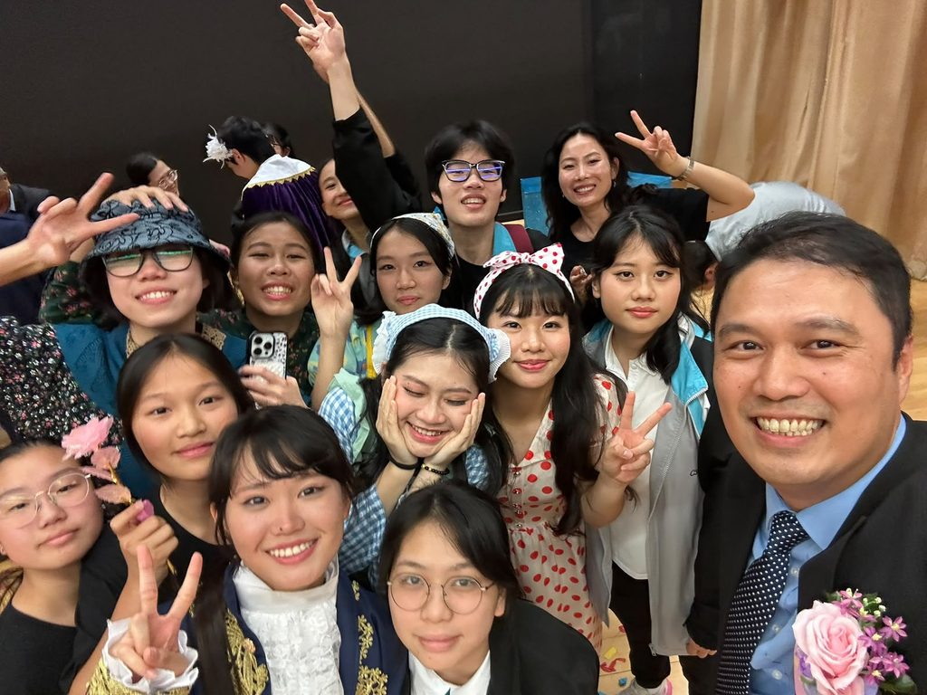 一個孩子的成長,從來不只發生在課本與考卷之中。鐘聲慈善社胡陳金枝中學王金鏗校長深信,學校應該是一個讓學生探索自己、建立信心、學會堅持的試煉場與避風港。有人在音樂劇中第一次敢於站到台前,有人在合球場上明白團隊合作的力量,也有人透過中樂、沙畫、無人機足球和國際交流,慢慢找到屬於自己的未來方向。這所學校的故事,或許正提醒我們:教育的真正價值,不在考卷上的分數,而在於孩子能否被看見、被鼓勵,並從經歷中長出面向未來的能力和韌性。